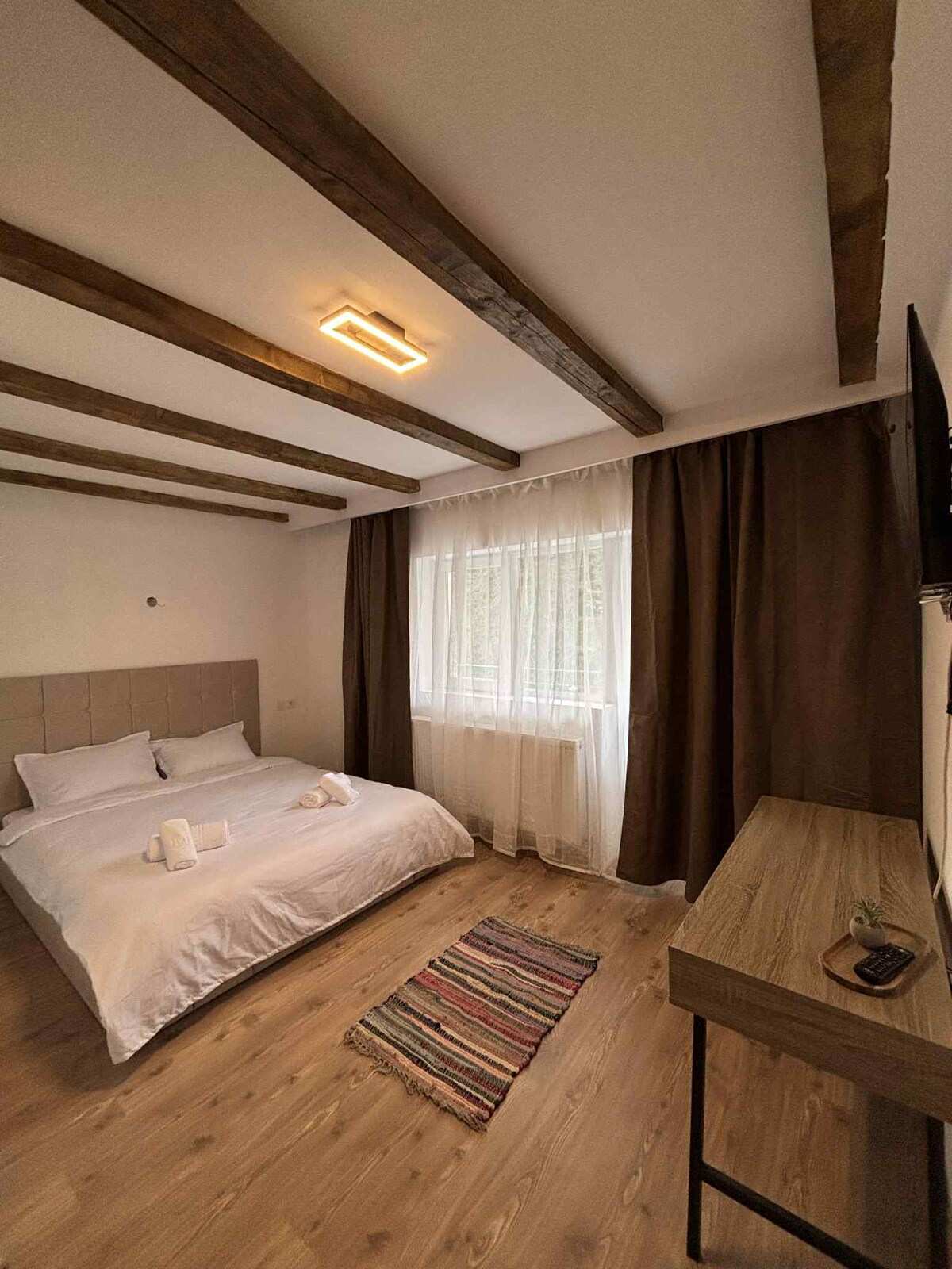 Cameră cu pat dublu, grinzi de lemn aparente și draperii